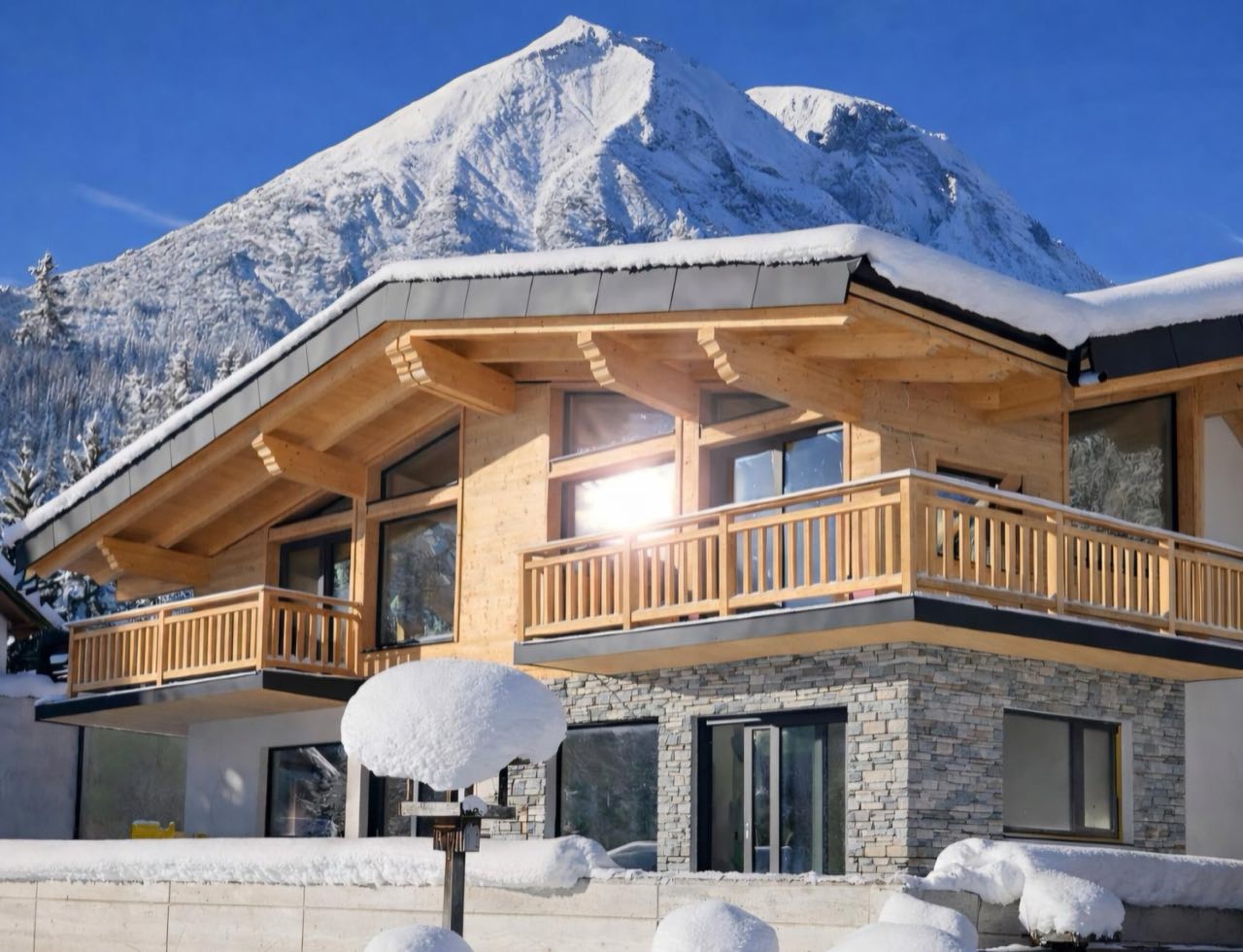 Neues JOWI-Chalet mit Steinsockel und Holzbalkon im Winter